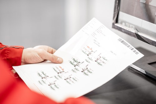 Auto mechanic holding a paper with geometry wheel alignment results at the car service, close-up view